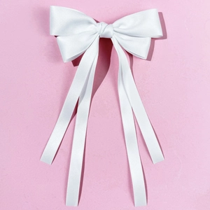 Detail of a large white satin bow hair clip with four long elegant flowing ribbons