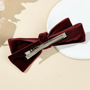 Detail view of the silver metal duckbill clip on the back of a burgundy velvet bow hair clip