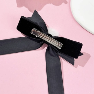 Dettaglio del fiocco in velluto nero con pompon bianco e molletta a coccodrillo in argento