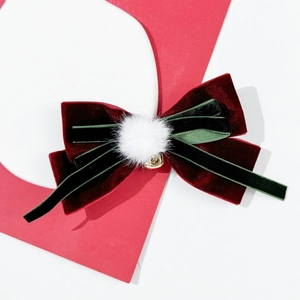 Detail of red velvet bow hair clip with white pompom and gold bell for Christmas