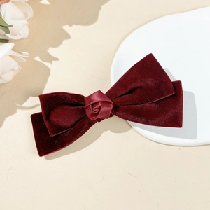 Detail of vintage red velvet bow hair clip with a central satin rose flower ornament