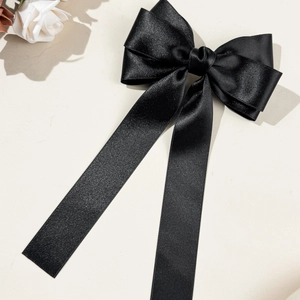 Detailansicht einer eleganten schwarzen Satin-Haarschleife mit langen fließenden Bändern
