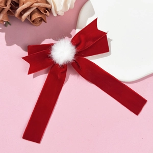 Dettaglio del fermaglio per capelli a fiocco in velluto rosso con pompon bianco soffice