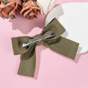 Elegant olive green wool bow hair clip with silver metal alligator clip on pink background