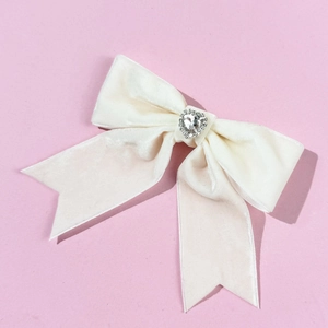 Detailed macro view of the cream velvet bow hairpin with a sparkling rhinestone heart