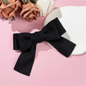 Detailed macro view of black wool bow hair clip texture and elegant velvet fabric finish