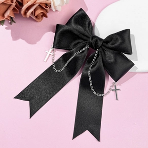 Gothic black satin bow hair clip featuring a metal chain and cross pendant on pink surface