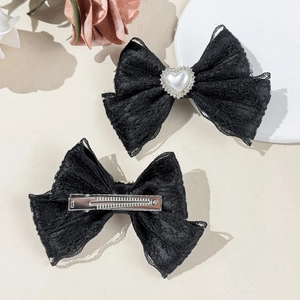 Vue détaillée de barrettes noeud en dentelle noire avec perles coeur et pinces crocodiles