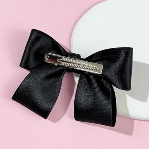 Detail view of double-layered black satin bow hair clip with silver metal alligator clip