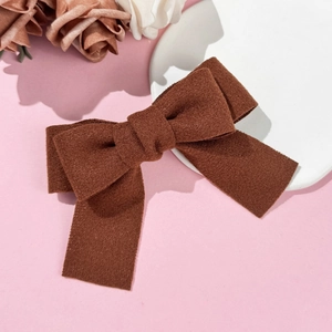 Close-up of brown velvet bow hair clip with ribbons on an elegant pink background