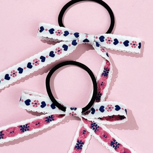 Close-up of floral embroidery and white lace edges on two ballet style hair bows