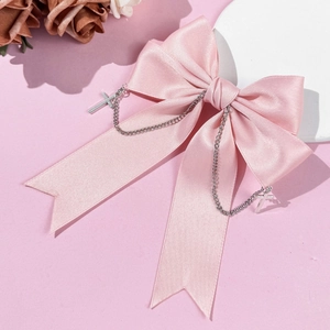 Pink satin bow hair clip with silver cross chains in gothic punk style on pink background