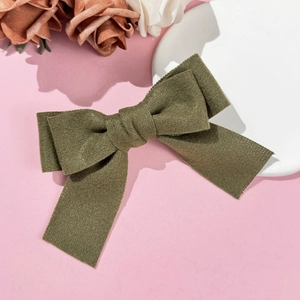 Detailed texture of an army green wool bow hair clip on a pink decorative background