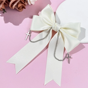 Close-up of white satin bow hair clip with silver metal chains and cross pendants