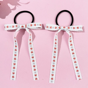 Detail of floral embroidered long bow hair ties with red hearts on a light pink background