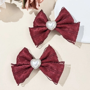 Détail de barrettes en dentelle rouge vin avec perle en cœur et strass brillants