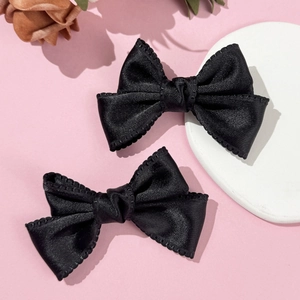 Détail de barrettes nœud noir avec bords en dentelle sur un fond rose doux