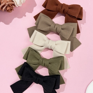 Elegant wool bow hair clips set in five earthy colors on a soft pink background