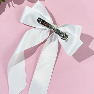 Pince à cheveux élégante en satin blanc avec fermoir en métal sur fond rose pastel