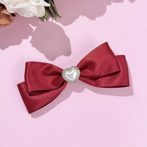 Makroaufnahme der roten Satin-Schleife mit Herzperle und funkelnden Strass-Details