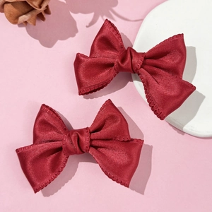 Paire de barrettes nœuds en satin rouge style ballet doux sur fond rose esthétique