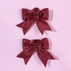 Detailed macro view of the burgundy satin rose bow hair clip with elegant ribbon texture
