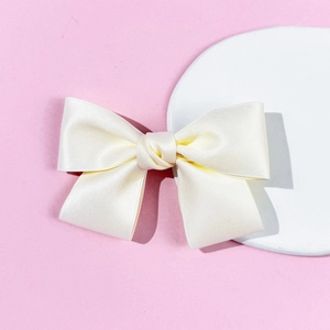 Elegant cream satin bow hair clip on a stone pedestal for a vintage aesthetic style
