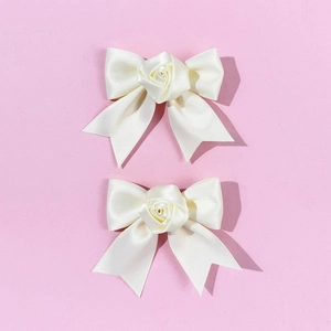 Detailed view of handmade cream satin bow hair clips with delicate central rose petals