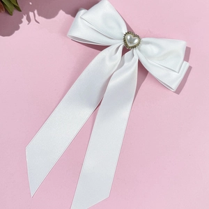Détail d'un nœud en satin blanc avec perle en cœur et bordure dorée de style rétro