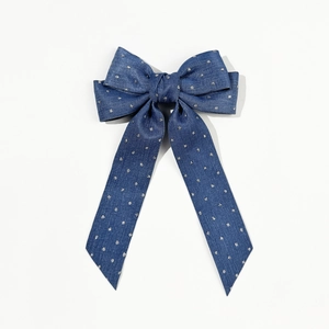 Détail d'un nœud papillon en denim bleu avec pois argentés et rubans longs pendants