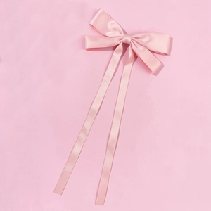 Detail view of glossy pink satin ribbon hair clip with elegant long trailing streamers