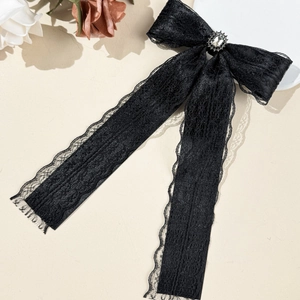 Detail of black lace bow hair clip with sparkling rhinestone and long hanging ribbons