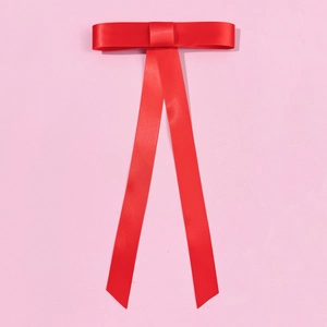 Barrette à cheveux élégante en satin rouge avec longs rubans sur fond rose doux