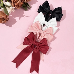 Lace-edged bow hair clips in black, white, pink, and burgundy on a romantic background