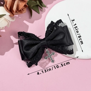 Detailed view of Gothic bow hair clip with lace and a vintage silver cross pendant