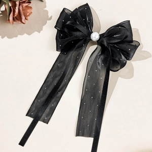 Detail einer eleganten schwarzen Tüll-Haarklammer mit weißer Perle und funkelnden Strass