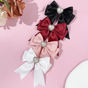 Satin bow hair clips with heart pearls in black, red, pink, and white on pink background