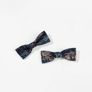 Detailed view of two denim bow hair clips with rose gold sequins on a plain white background