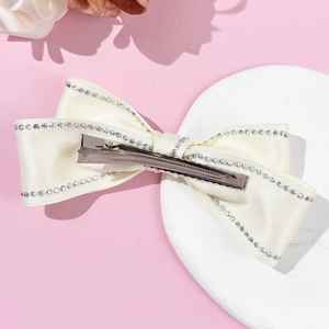 Détail du nœud papillon en satin crème avec double rangée de strass scintillants