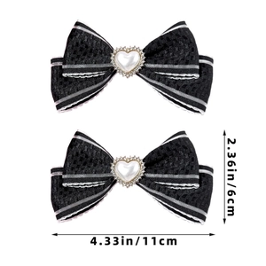 Détail de deux barrettes à nœud noir avec bords rayés et accents de perles en cœur