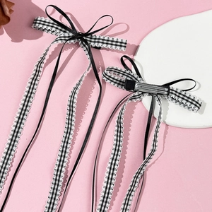 Pair of sweet black and white checkered bow hair clips with long ribbons on pink background