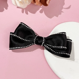 Barrette à nœud en satin noir élégante avec strass argentés sur plateau en marbre blanc