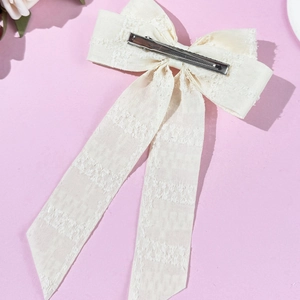 Detailed back view of off-white lace bow hair clip with ribbons and silver metal duckbill clip