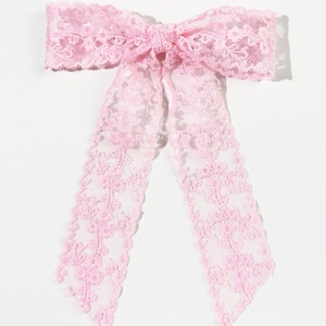 Dettaglio di un fiocco per capelli in pizzo rosa con lunghi ed eleganti nastri fluenti
