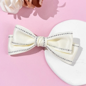 Barrette nœud en satin blanc élégant avec strass argentés sur plateau décoratif