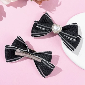 Détail de barrettes noeuds noirs avec perles en coeur et pinces crocodiles