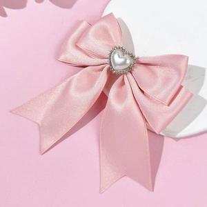 Detailed close-up of pink ribbon hair clip with pearl heart and rhinestone accents