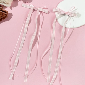 Detail showing pink plaid bow hair clips with long ribbons and scalloped edges