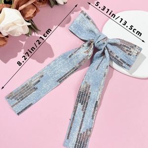 Detail of denim bow hair clip with sequins and long tassels, measuring 21cm by 13.5cm