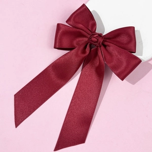 Détail d'un nœud à cheveux en satin bordeaux avec petite rose en soie et longs rubans